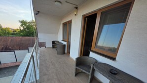 Un balcon doté d’un sol carrelé, de meubles en osier et d’une fenêtre donnant sur un paysage verdoyant.