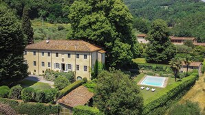 A large, two-story building with a tiled roof, surrounded by lush greenery and a swimming pool. - Villa Spada - countryside - Pool - 30 min from the Sea (Toscana)