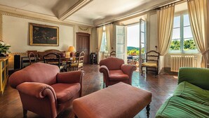 A spacious room with a dining area, a green sofa, and a view of the outdoors. - Villa Spada - countryside - Pool - 30 min from the Sea (Toscana)