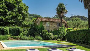 A pool area with two lounge chairs, a stone house, and lush greenery. - Villa Spada - countryside - Pool - 30 min from the Sea (Toscana)