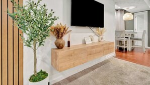 Una sala de estar moderna con una consola de madera, un televisor montado y una planta en maceta.