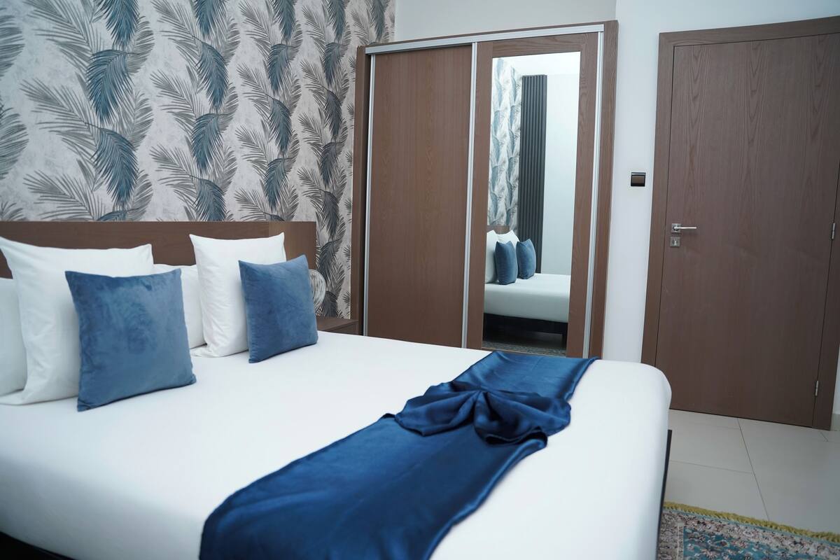 A hotel room with a bed, a wardrobe, and a mirror.