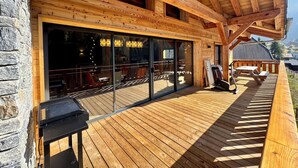 Eine Holzhütte mit einer Terrasse, großen Schiebeglastüren und einer Steinwand.