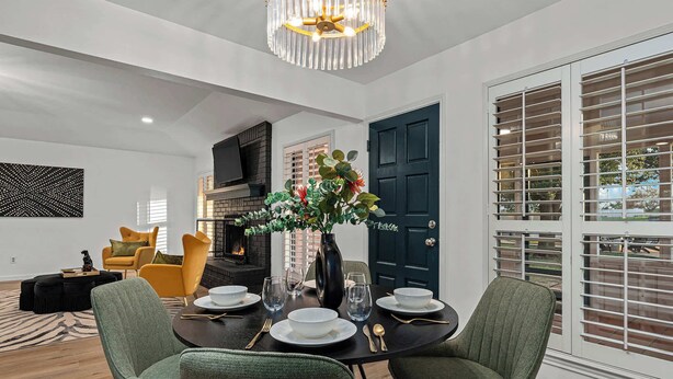 A dining area with a table set for four, a vase with flowers, and a modern chandelier. - Bubble Bungalow - Cowboy Pool, Hot Tub & Firepit! (Fredericksburg)