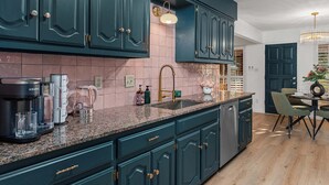 A kitchen with teal cabinetry, a granite countertop, a coffee maker, and a sink. - Bubble Bungalow - Cowboy Pool, Hot Tub & Firepit! (Fredericksburg)