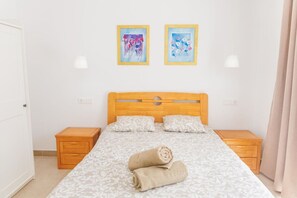 A bedroom with a wooden bed, two bedside tables, and two wall-mounted lamps.