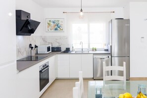 A modern kitchen with a dishwasher, microwave, oven, and a stainless steel refrigerator.