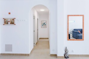 Un couloir avec un tableau encadré représentant un canapé et une porte ornée de motifs floraux.