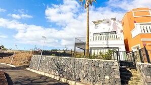 Un bâtiment situé sur la côte, doté d’un mur en pierre, d’un palmier et surplombant un ciel dégagé.
