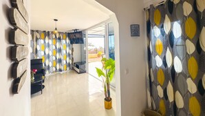 Un hall d’entrée spacieux au design moderne, agrémenté d’un mur à motifs, d’une plante en pot et d’une vue sur un espace extérieur.