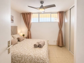 A bedroom with a bed, curtains, a ceiling fan, and a window. - Sun-Kissed Vacation Home: 3BR Retreat by the Ocean (Callao Salvaje)
