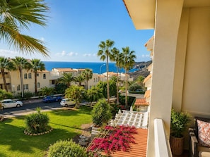 A balcony with a view of a coastal area, including a road with parked cars and palm trees. - Sun-Kissed Vacation Home: 3BR Retreat by the Ocean (Callao Salvaje)