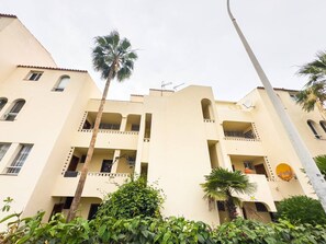 Un edificio de varios pisos con balcones, antenas parabólicas y una palmera.