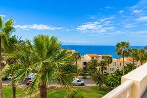 Un quartier résidentiel en bord de mer, avec des palmiers, un ciel bleu azur et une vue sur l’océan.
