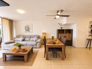 Un salon moderne comprenant un canapé, une table basse, une table à manger et un ventilateur de plafond.