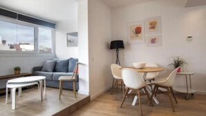 Un salon moderne comprenant un canapé, une table à manger avec des chaises, une table basse et une lampe.