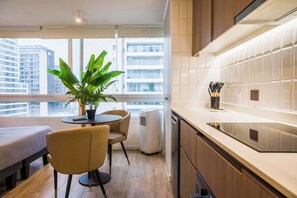 A modern kitchen with a dining area, a potted plant, and a view of a cityscape.
