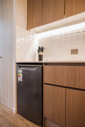 Une cuisine équipée d’un réfrigérateur encastré, de meubles de rangement en bois et d’un pare-feu en carrelage.