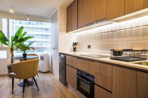 A modern kitchen with wooden cabinets, a built-in oven, and a dining area with a table and chairs.