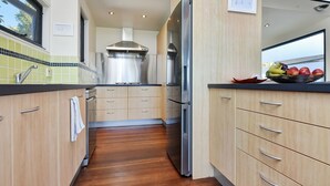 Eine moderne Küche mit Holzschränken, Edelstahlgeräten und einer gefliesten Spritzschutzwand.