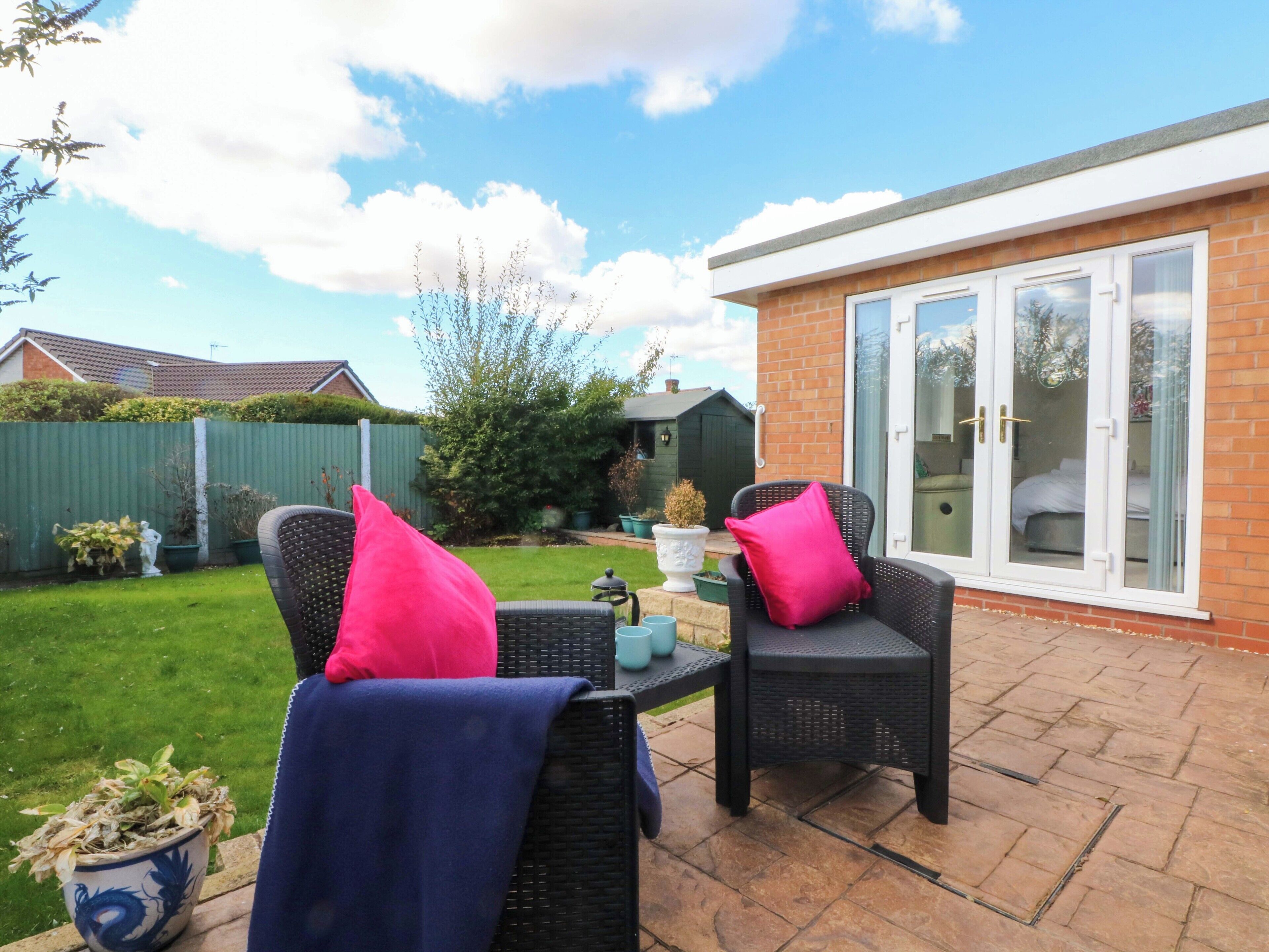 An outdoor patio area with wicker furniture and a glass door leading to a room.