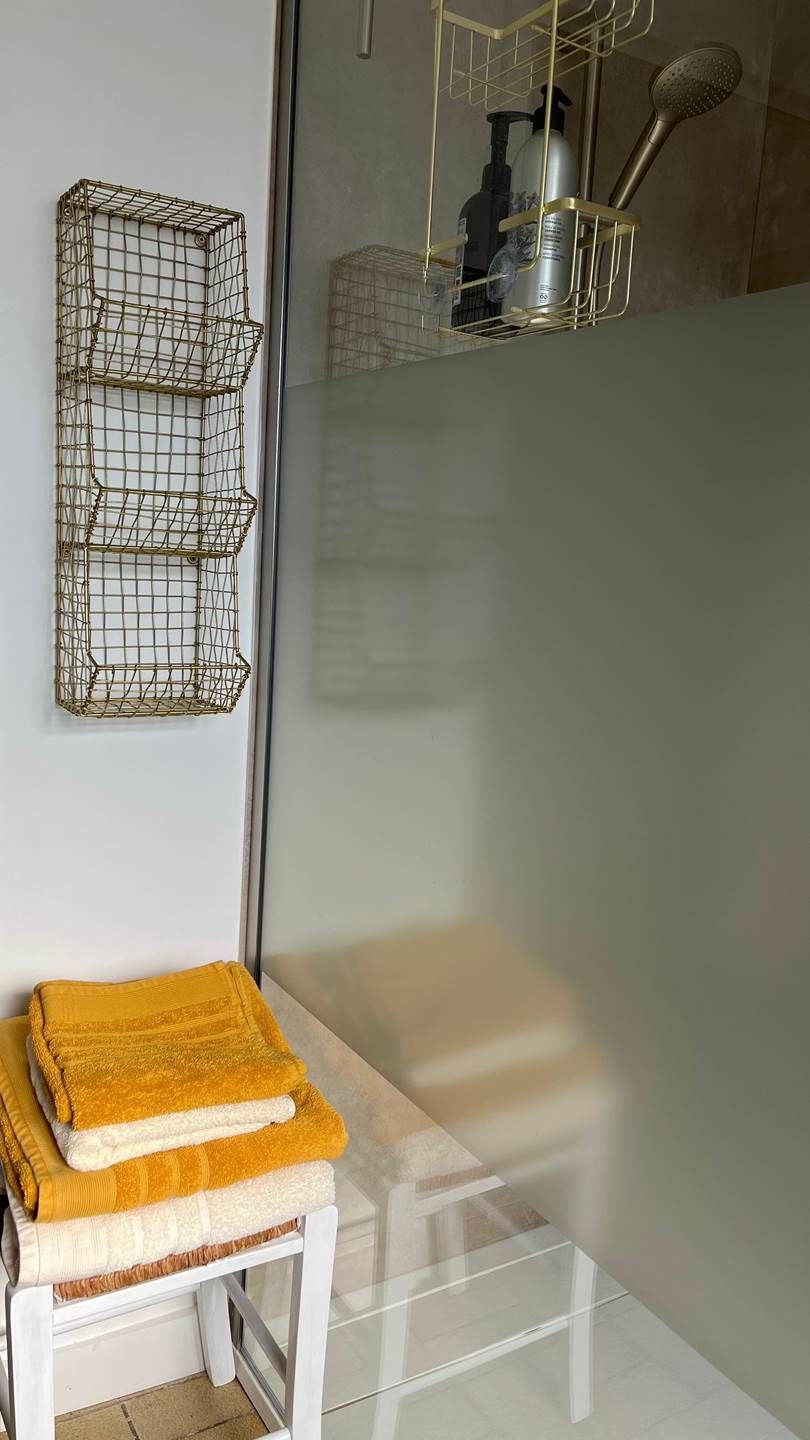 Une salle de bain avec une douche à parois de verre, un lavabo blanc et un porte-serviettes avec des serviettes.