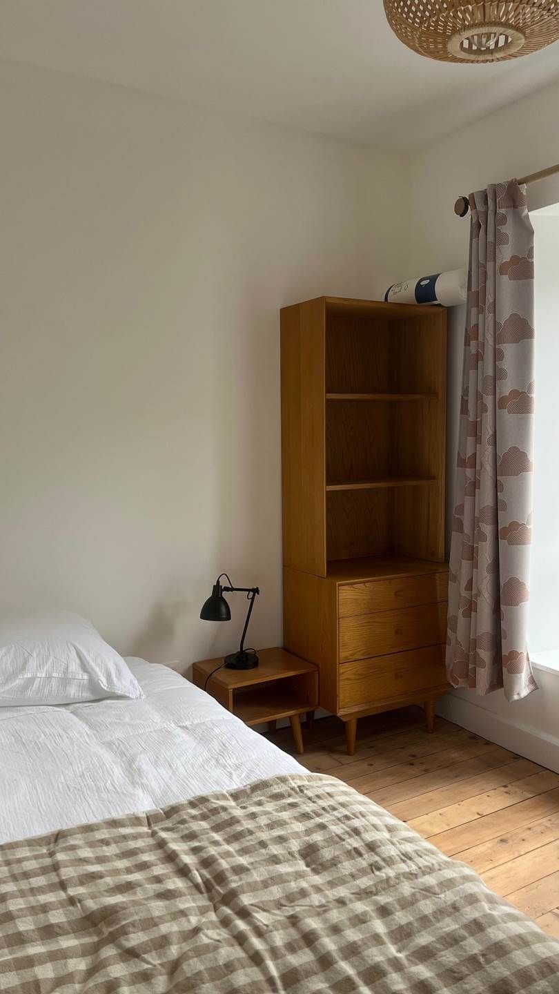 Ein Schlafzimmer mit einem Bett, einem Nachttisch aus Holz, einem Schreibtisch und einem Kleiderschrank.