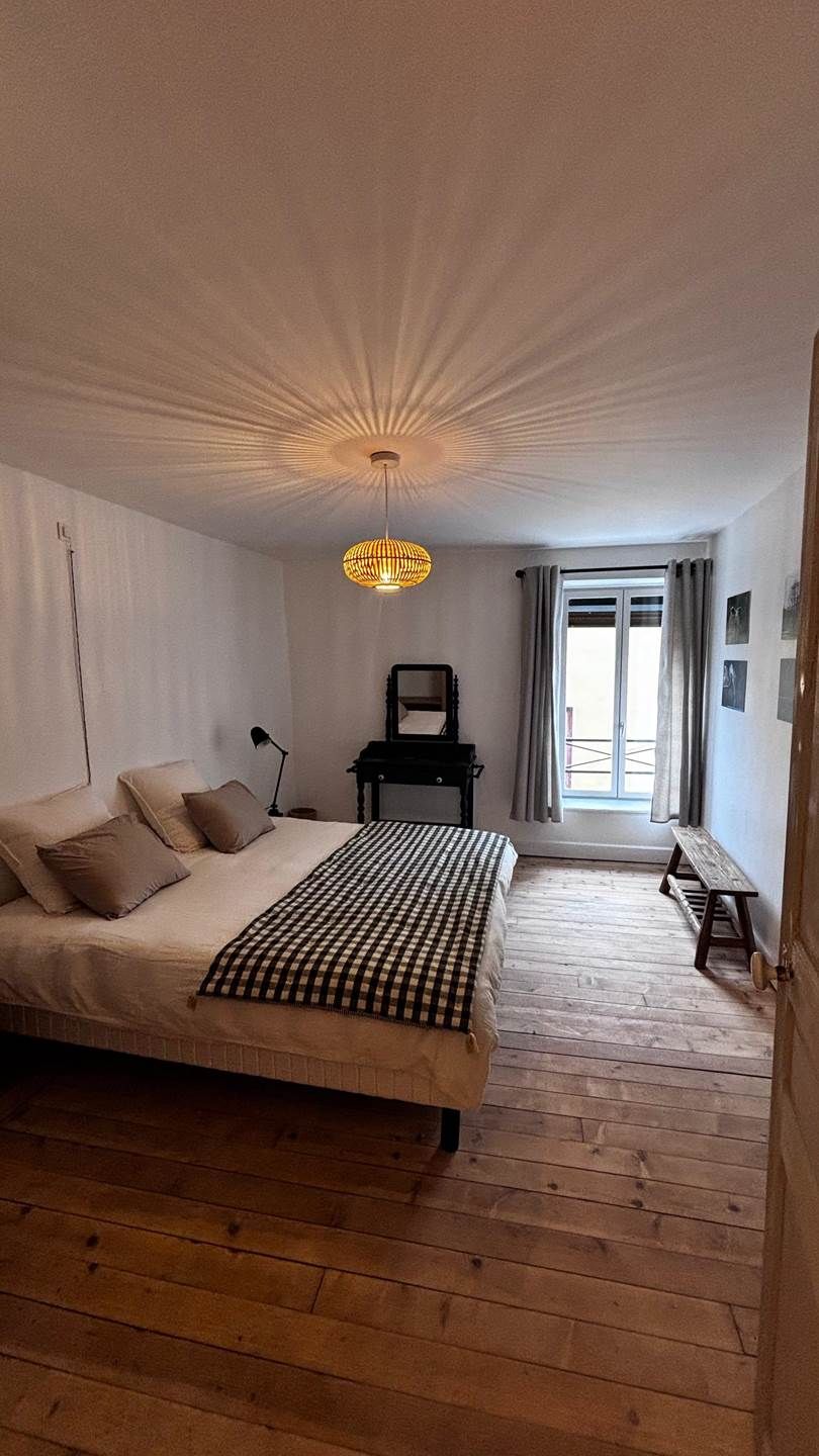 Une chambre à coucher avec un lit, un bureau, une chaise et une fenêtre avec des rideaux.