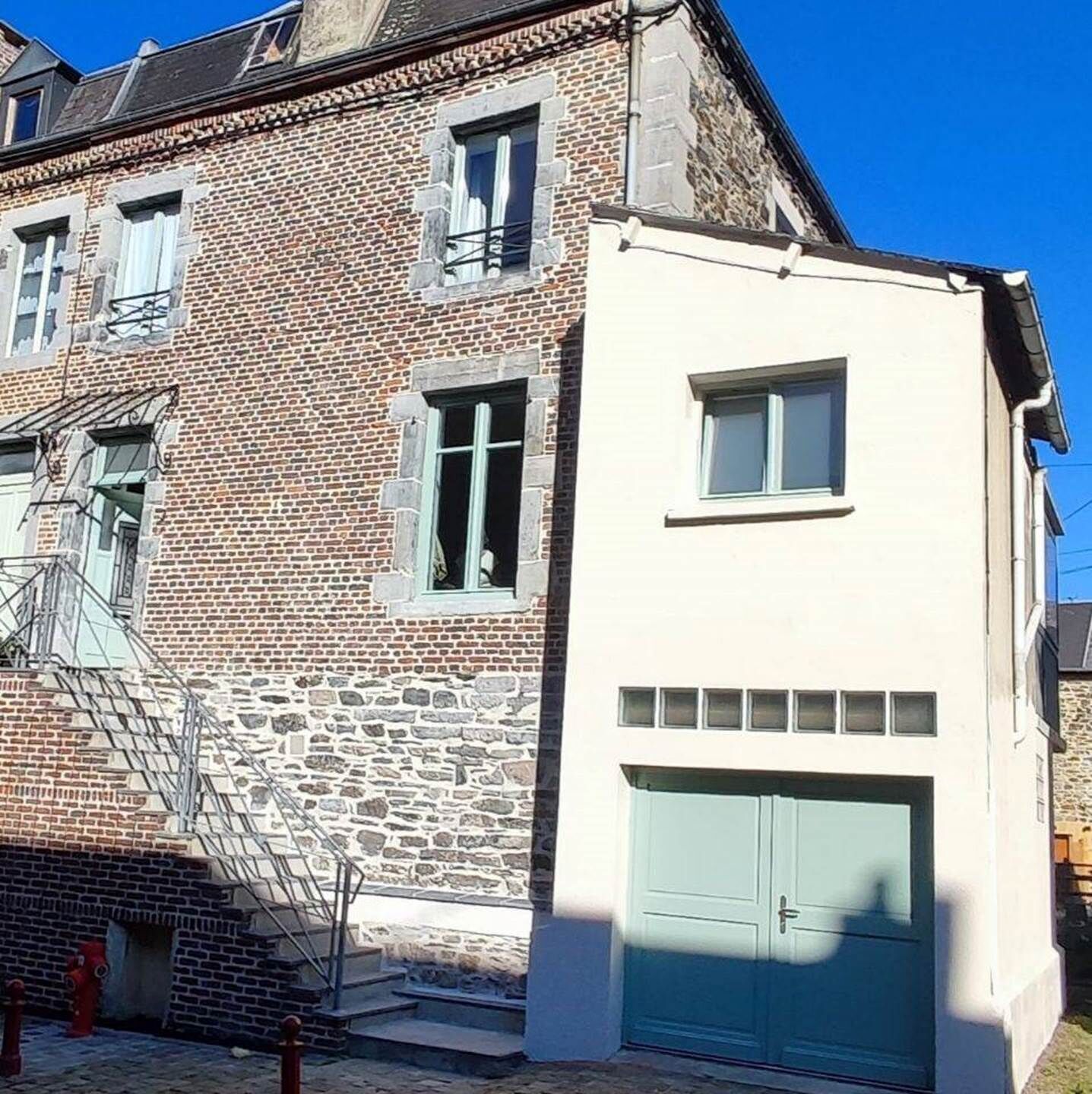 A two-story building with a brick facade and a white section with a garage.