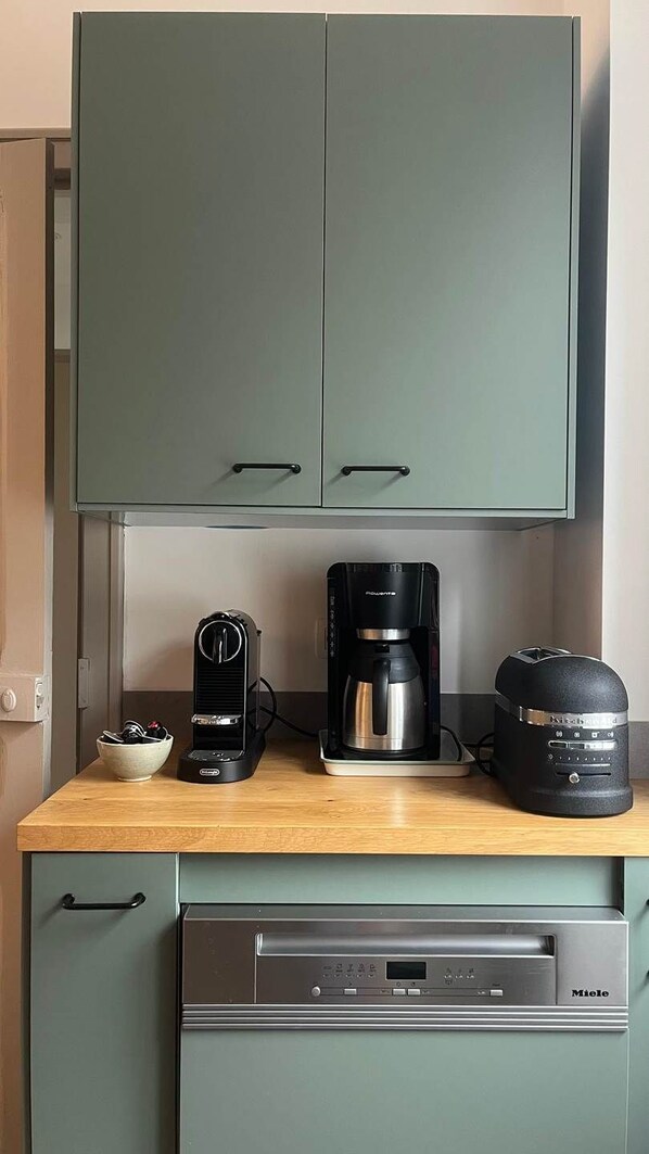 Une petite cuisine équipée d’une machine à café, d’un grille-pain et d’un lave-vaisselle.