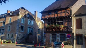 A street with traditional European architecture, including a building with a brick facade and a balcony with flowers.