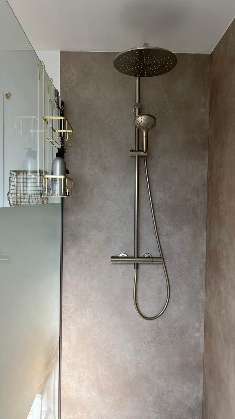 A modern shower with a handheld hose and a round showerhead mounted on a wall.