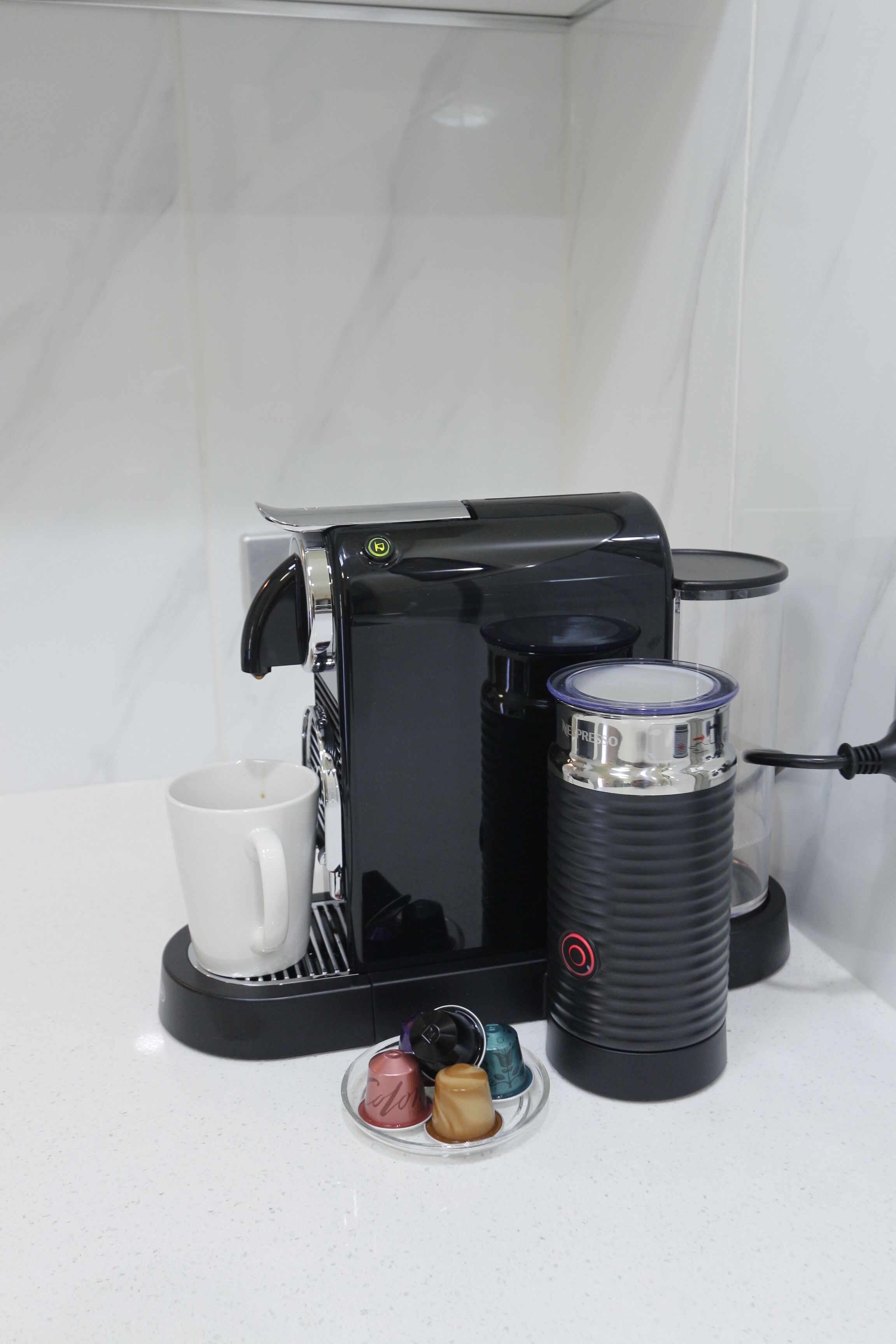 Une machine à café, une tasse et un thermos posés sur un comptoir.