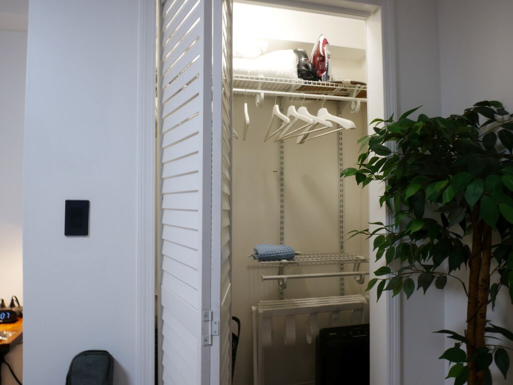 Un placard avec une tringle pour suspendre les vêtements, des étagères et un radiateur.
