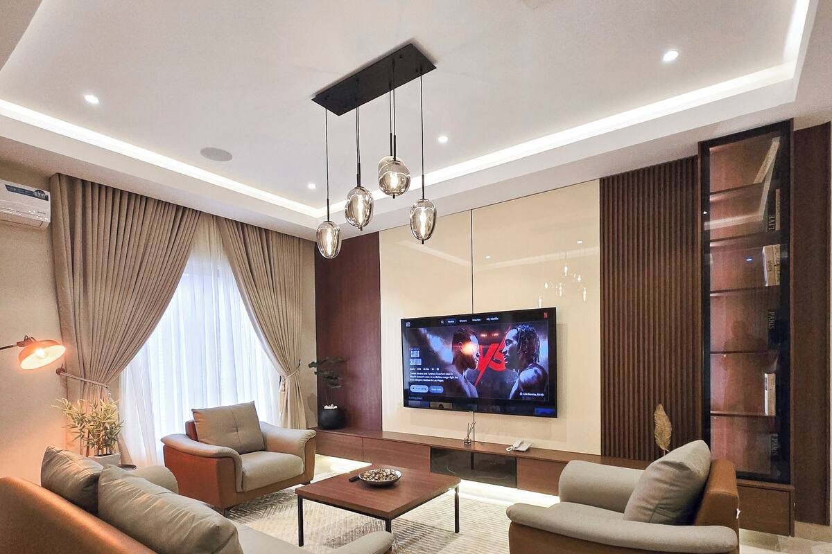 A modern living room with a flat-screen TV, sofas, a coffee table, and a patterned rug.