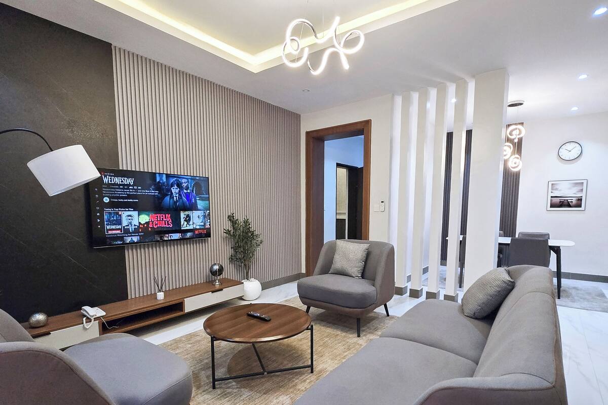 A modern living room with a flat-screen TV, a sofa, a coffee table, and a lamp.
