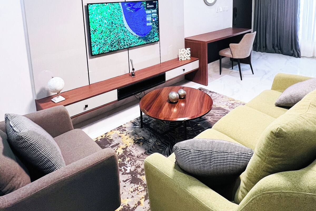 A modern living room with a flat-screen TV, a wooden coffee table, and two sofas with patterned cushions.