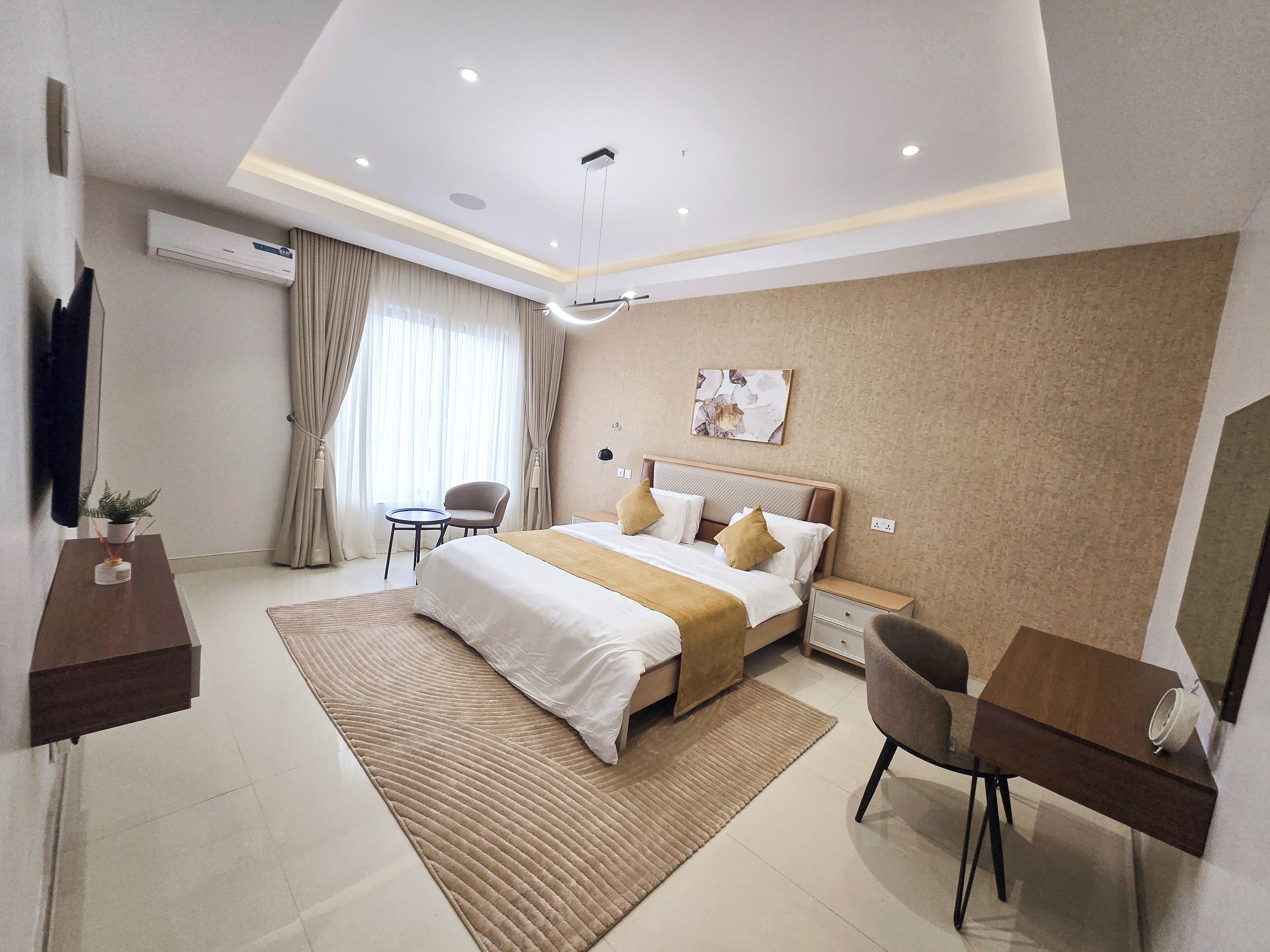 Une chambre d’hôtel moderne équipée d’un grand lit, d’un bureau, d’une chaise, d’une télévision et d’un appareil de climatisation.