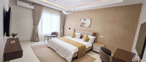 Une chambre d’hôtel moderne équipée d’un grand lit, d’un bureau, d’une chaise, d’une télévision et d’un appareil de climatisation.