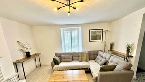 A modern living room with a sectional sofa, a wooden coffee table, a small side table, and a floor lamp.