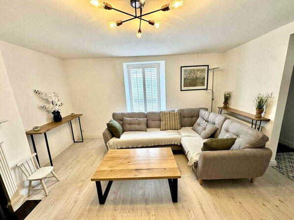 A modern living room with a sectional sofa, a wooden coffee table, a small side table, and a floor lamp.