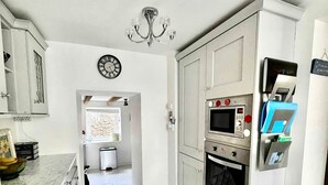 A modern kitchen with white cabinetry, a built-in oven, and a microwave.