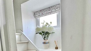 A staircase with a white railing leading to a landing with a window.