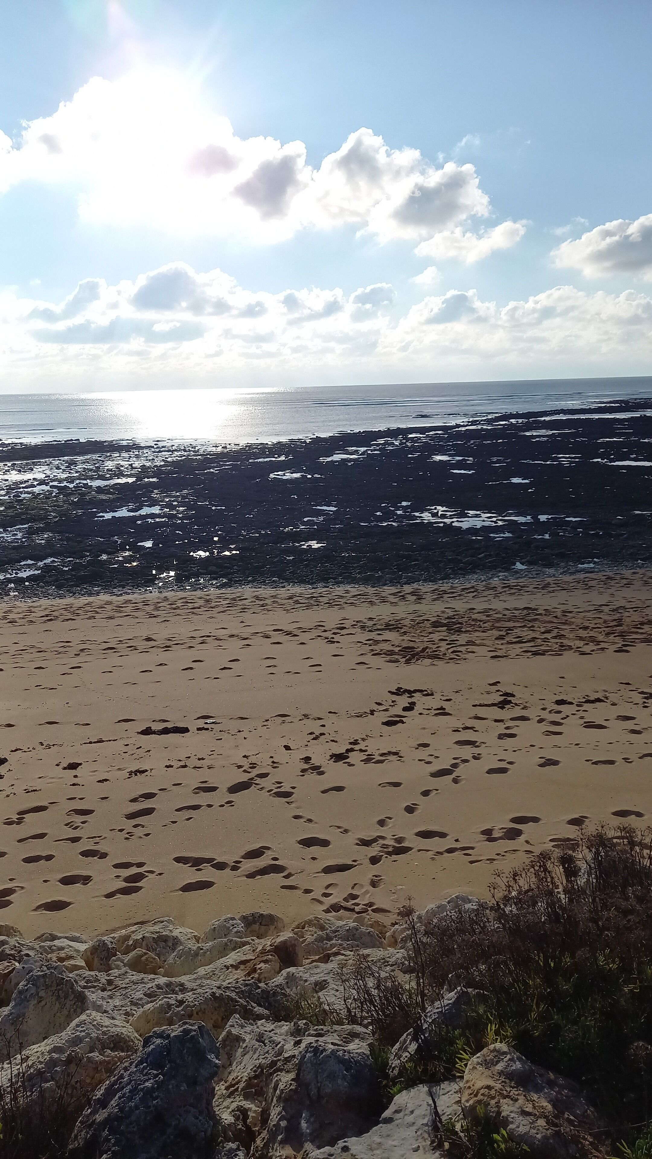 Une plage parsemée d’empreintes et de rochers.