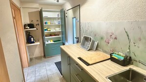 A kitchen with a wooden countertop, a stainless steel sink, and a green cabinet.