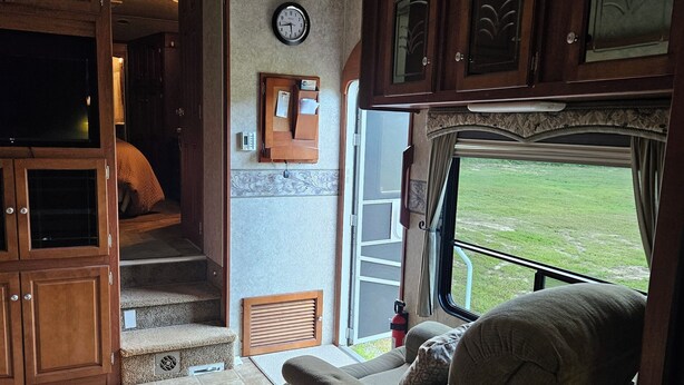 A cozy RV interior with a comfortable seating area, a clock, and a view of the outdoors. - Welcoming RV with AC in charming Farmerville. (Farmerville)