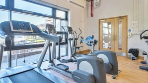 Una palestra con tapis roulant, ellittiche e una porta che dà su un'altra stanza.