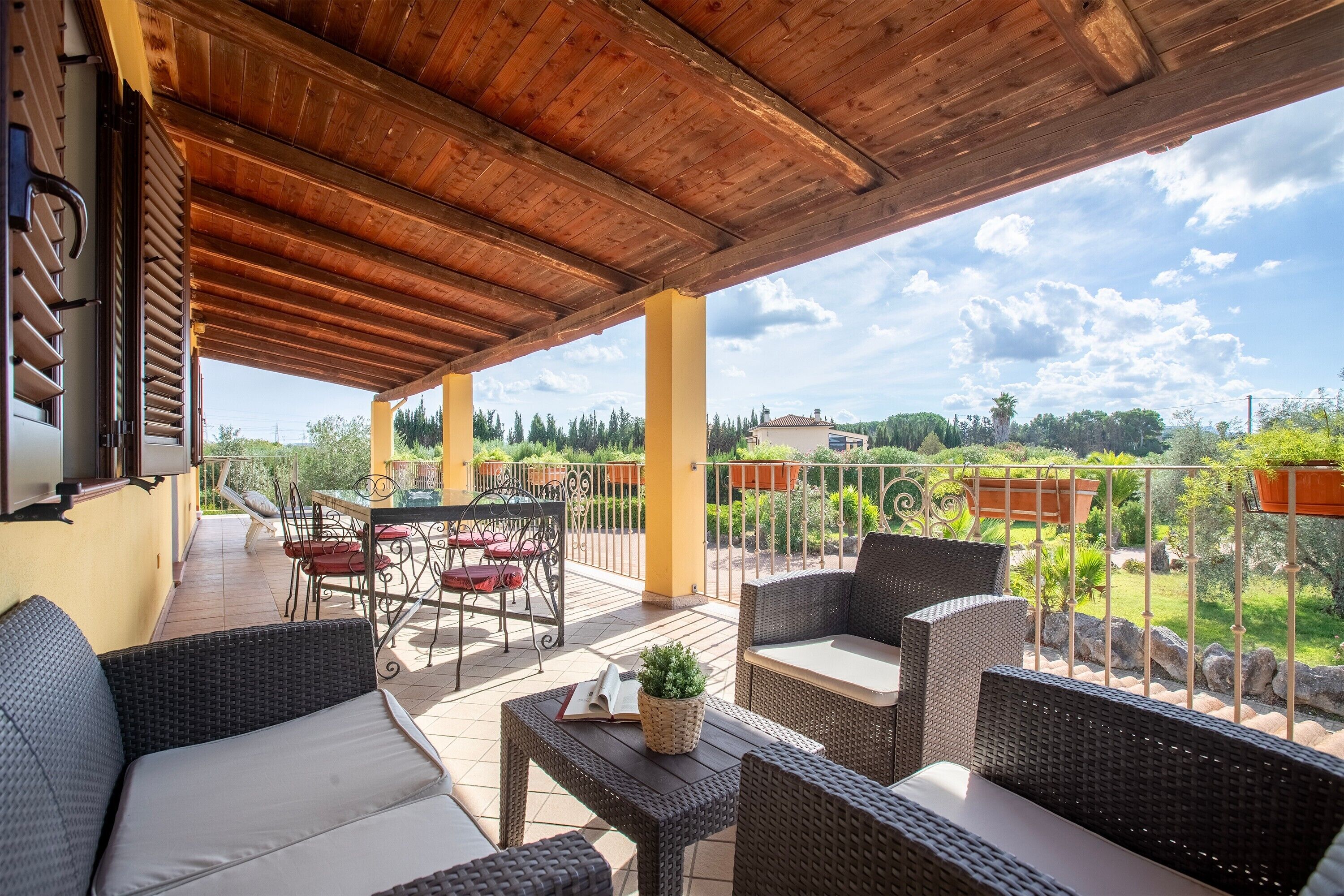 An outdoor patio with wicker furniture, a table, and a view of the surrounding landscape.