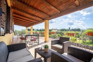 Une terrasse extérieure aménagée avec des meubles en osier, une table et une vue sur le paysage environnant.