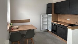 A compact kitchen with a wooden table and chairs, a built-in oven, and black cabinets.